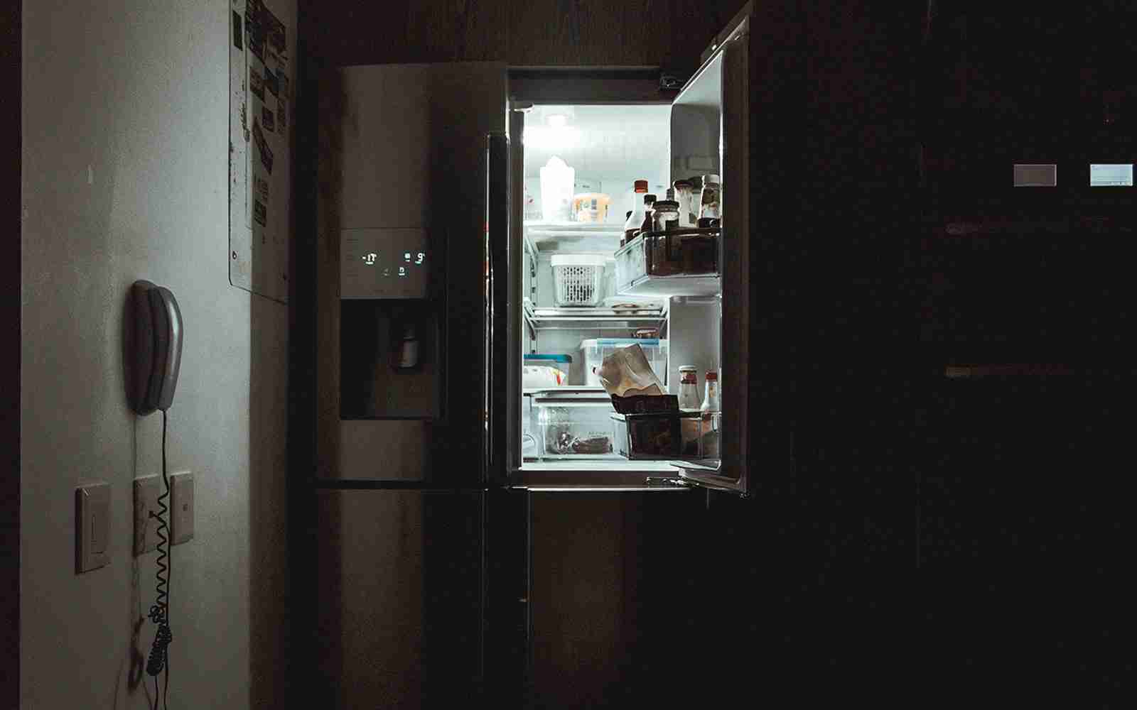 Photo of an open fridge surrounded by darkness